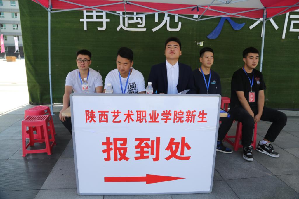 学生志愿者在新生报到指示牌前等待新同学的到来